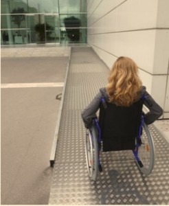 woman in wheelchair entering building using ramp