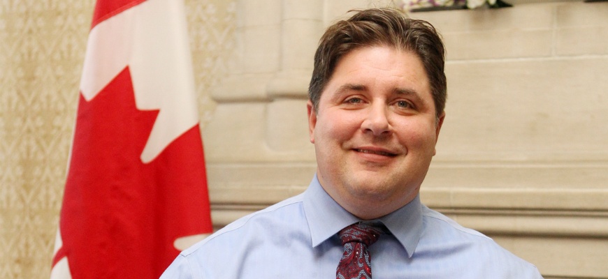 Kent Hehr headshot with Canadian flag in background