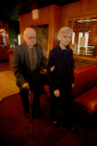 woman acting as sighted guide for man with a cane - hotel lobby