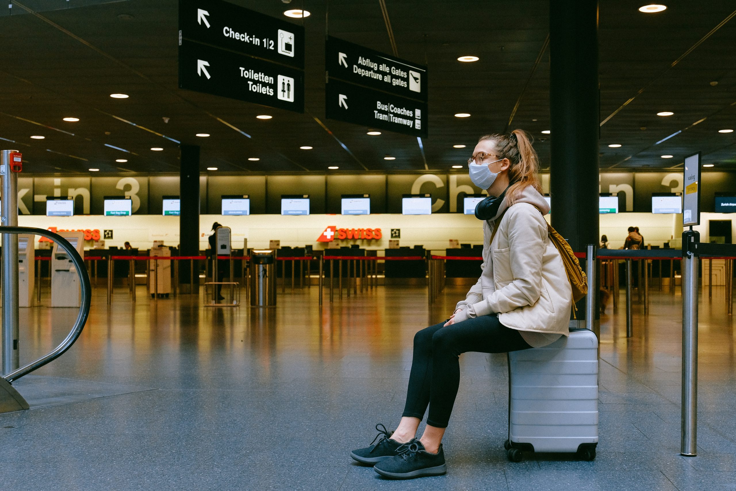 woman sitting on luggage waiting for air travel