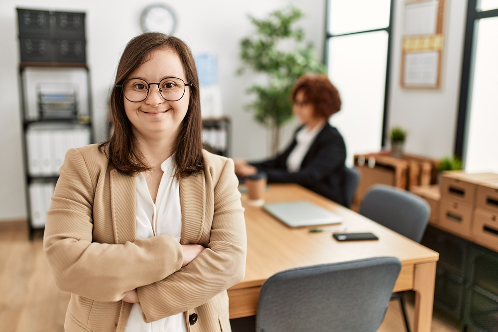 Down syndrome girl working at inclusive teamwork. Group of two women working at the office